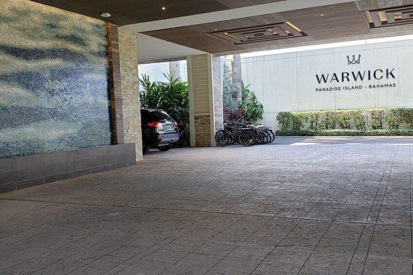 A building entrance with a sign reading 'WARWICK PARADISE ISLAND - BAHAMAS,' a tiled floor, and bicycles parked outside. 3