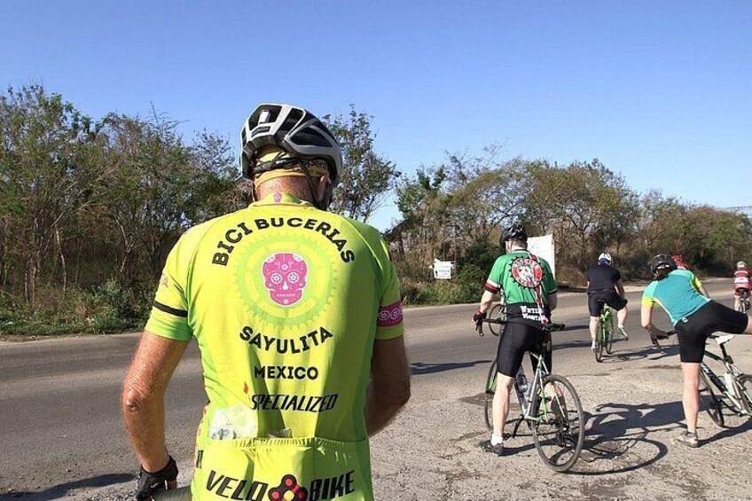 Un grupo de ciclistas en una carretera con árboles y un cielo despejado al fondo. 4