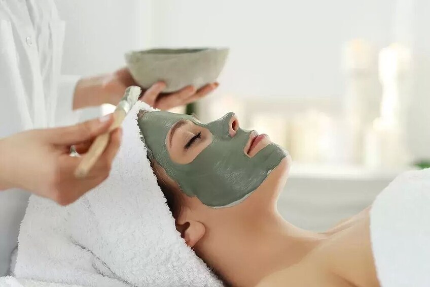 Een persoon krijgt een gezichtsbehandeling met een groene masker. 1