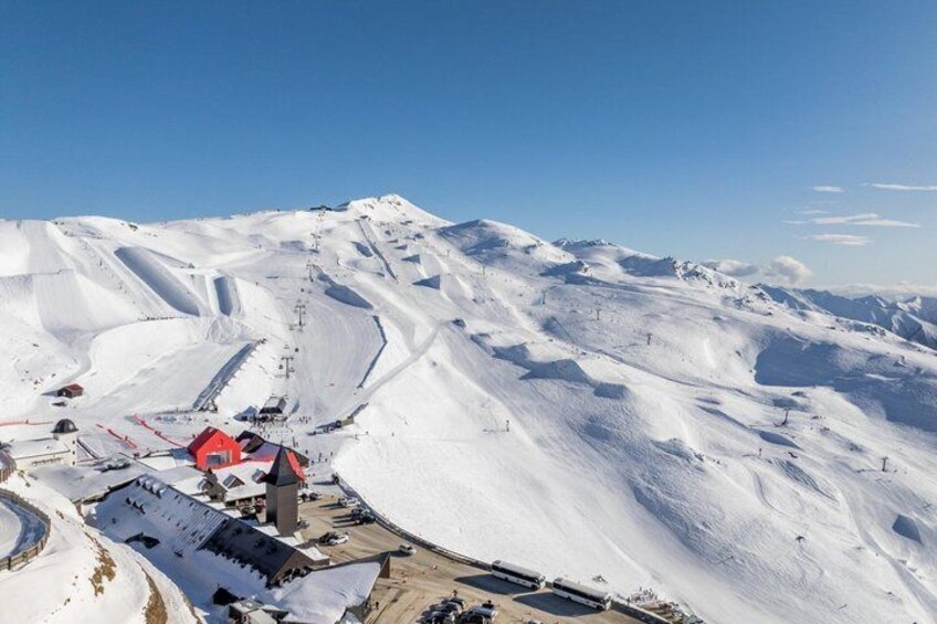 A snow-covered mountain with a red building and ski lifts. 1