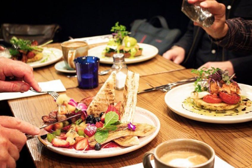 A dining table with various dishes, including a salad with greens and berries, a plate with a fish and vegetables, and a cup of coffee. 5