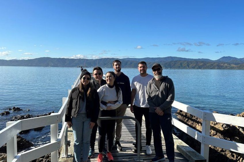 A group of people on a wooden pier by a lake with mountains in the background. 4
