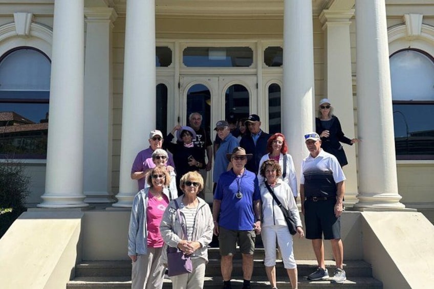 A group of people standing in front of a building with columns. 1