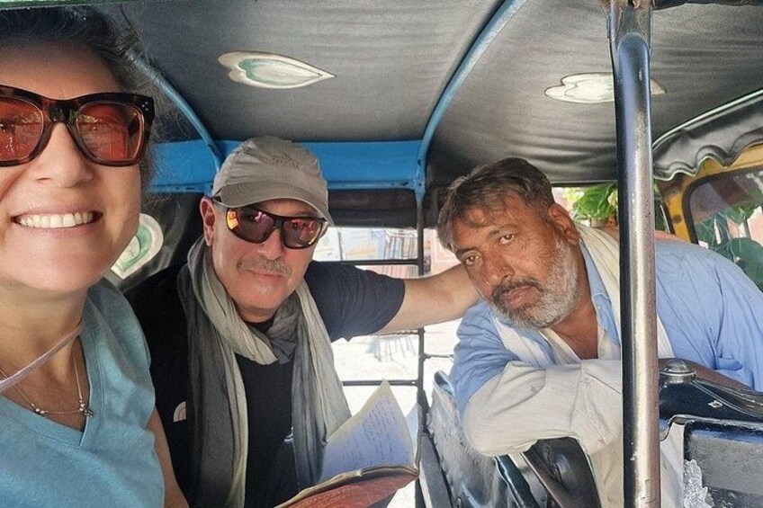 Tres personas dentro de un vehículo con interior azul, una barra metálica y una ventana. 4