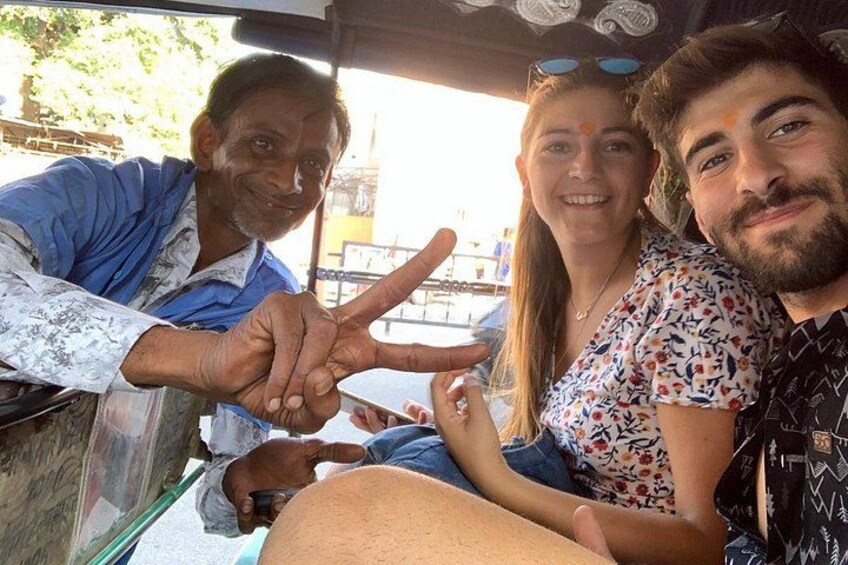 Tres personas sentadas en un vehículo, una de ellas haciendo un gesto de la paz. 3
