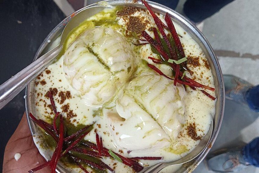 Una ciotola di cibo con salsa bianca cremosa, erbe verdi e spezie rosse. 1