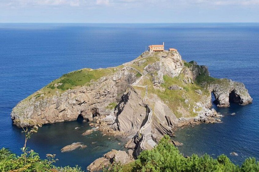 Una isla rocosa con un edificio en la cima, rodeada de aguas azules y transparentes. 3