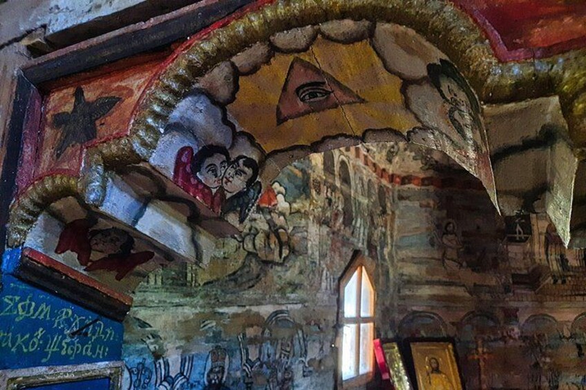 Ein Kircheninneres mit religiöser Ikonographie, darunter eine Darstellung von Jesus Christus, und einem Fenster, das natürliches Licht hereinlässt. 2
