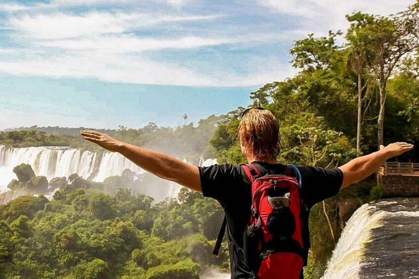 Eine Person mit ausgestreckten Armen, die einem Wasserfall entgegenblickt. 2