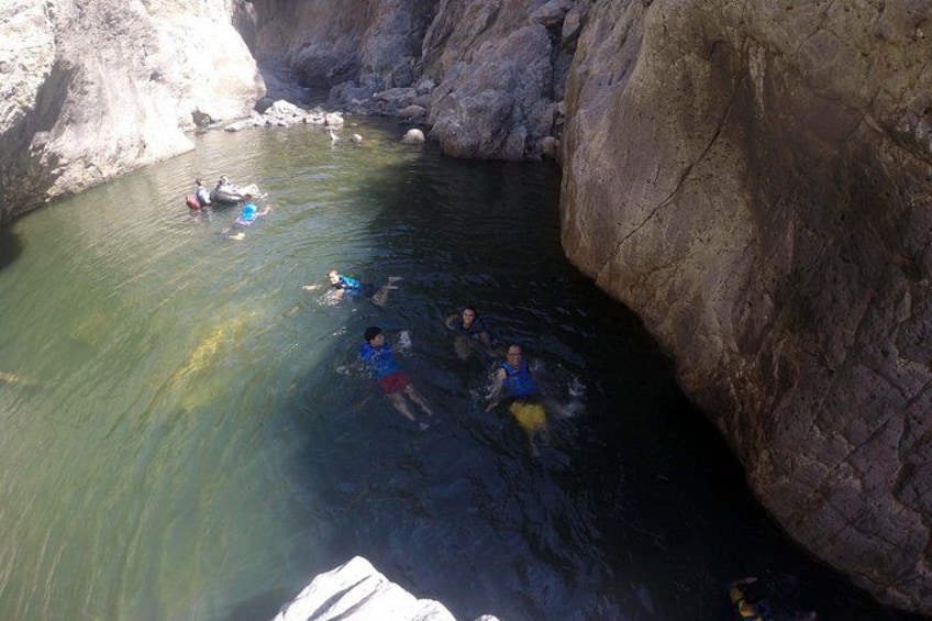 A group of people swimming in a natural water body surrounded by rocky cliffs. 5