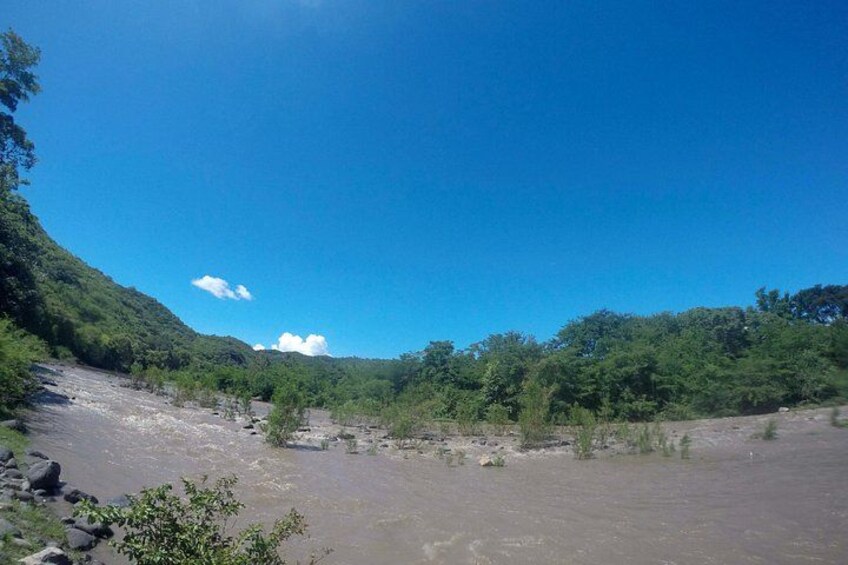 A river flowing through a forested valley with a clear sky. 4