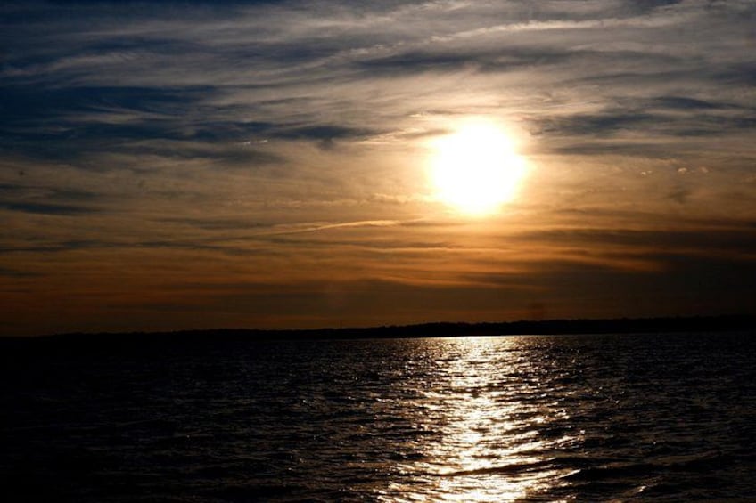 A sunset over a body of water with a visible sun reflection. 4
