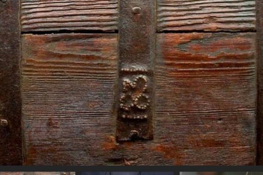 A weathered wooden surface with horizontal planks and a central metal strap with a decorative emblem. 2