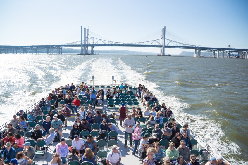 A boat with people on it, a bridge in the background, and water in the foreground. 4