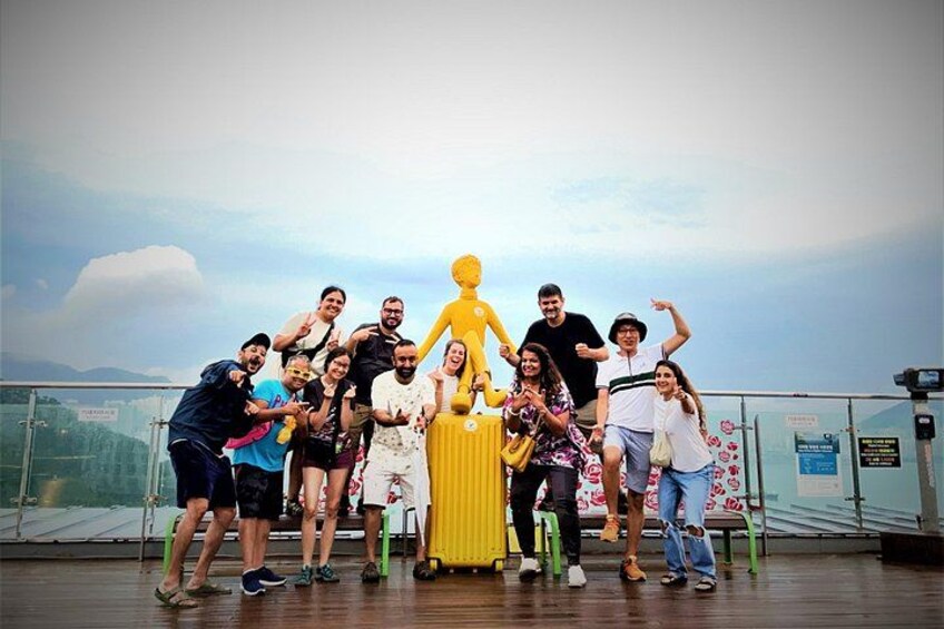 Un grupo de personas posando en un balcón con una vista panorámica de montañas al fondo. 3