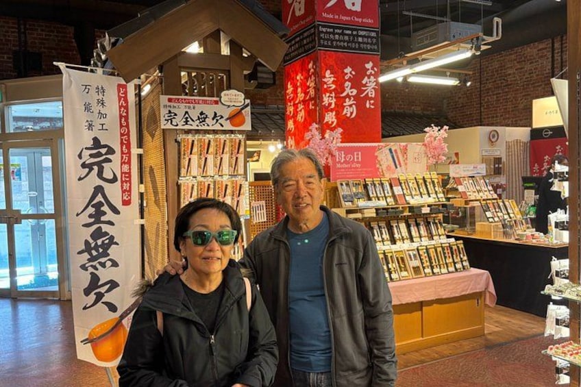 Two people standing in front of a shop with Japanese signage. 3