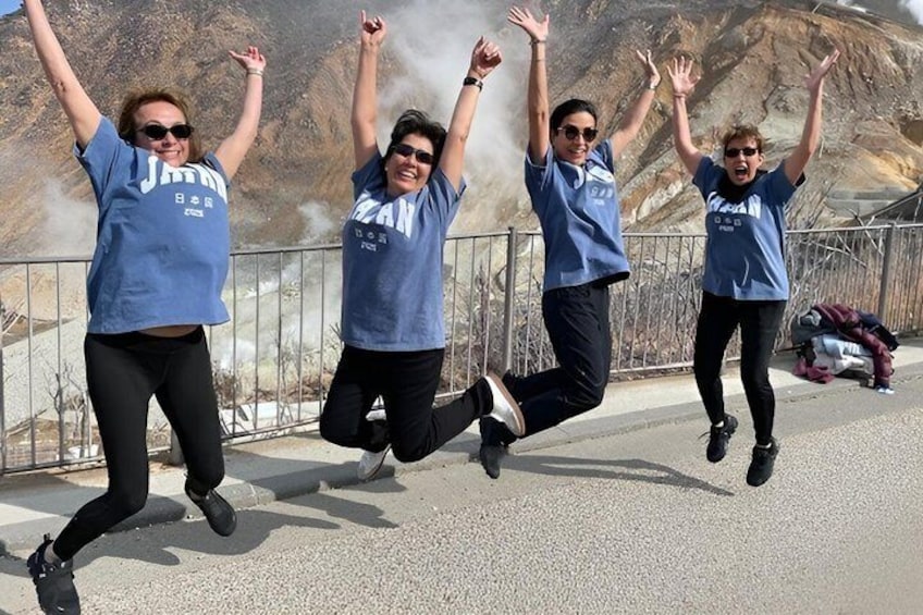 Four people jumping in mid-air on a bridge with a mountainous backdrop. 1