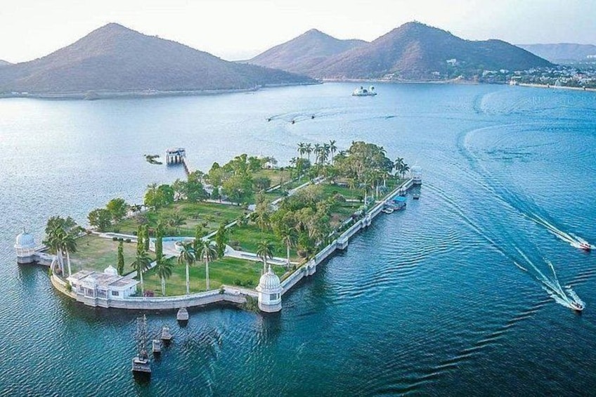 A large body of water with a small island featuring a white building, palm trees, and a dome structure. 1