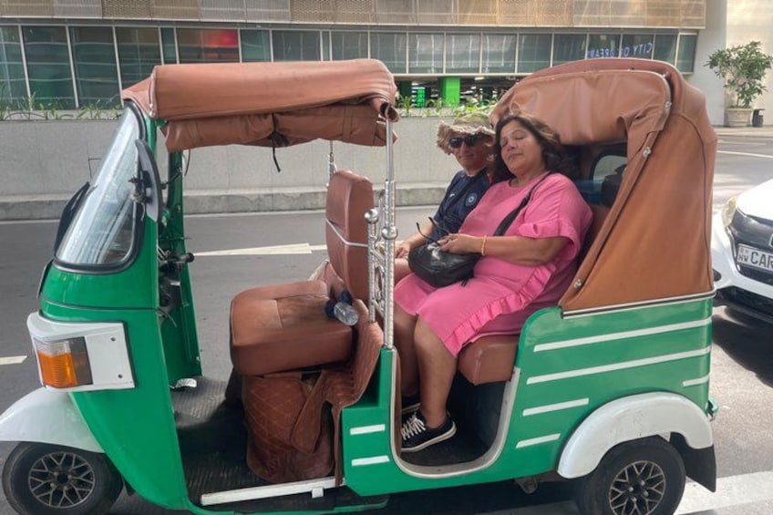 En grøn rickshaw med et brunt tag, der transporterer to passagerer. 3