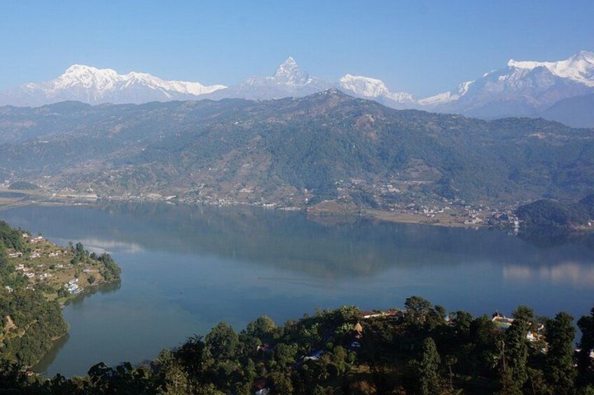 A lake surrounded by mountains, with a village on the left and a clear sky. 4