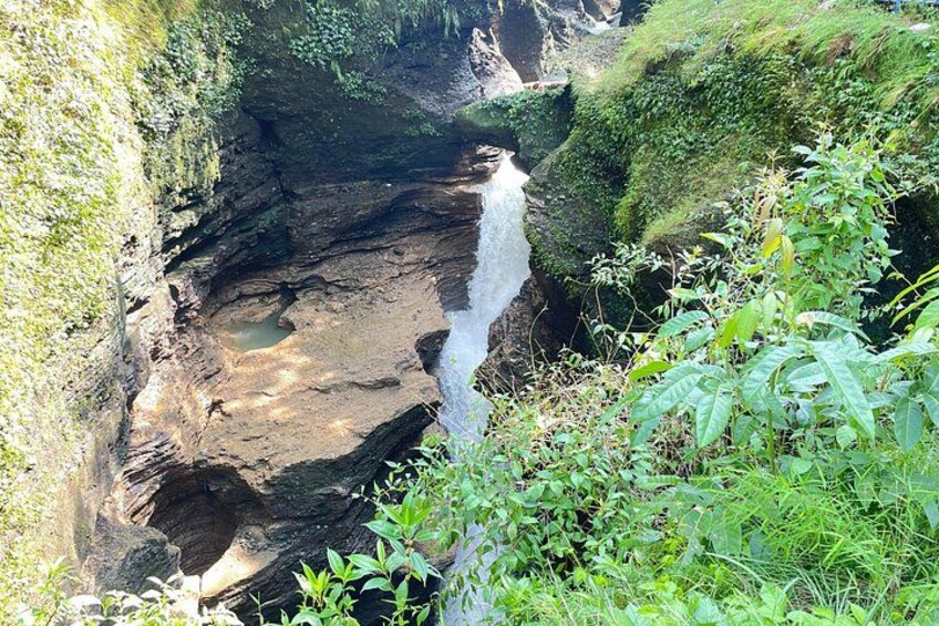 A waterfall in a rocky gorge with lush greenery. 2
