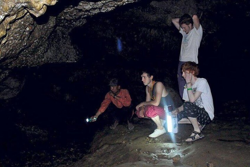 A group of people exploring a cave with a flashlight. 4