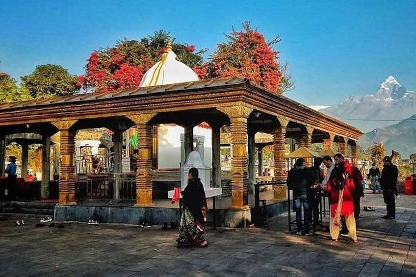 A traditional pavilion with a domed roof, surrounded by people and trees. 3