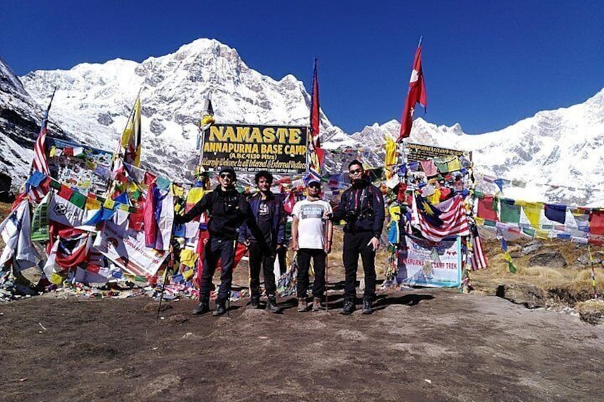 Un groupe de personnes se tient devant une enseigne ornée de drapeaux et de banderoles, avec des montagnes enneigées en arrière-plan. 5