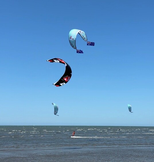 Multiple kitesurfers in the ocean with clear skies. 4