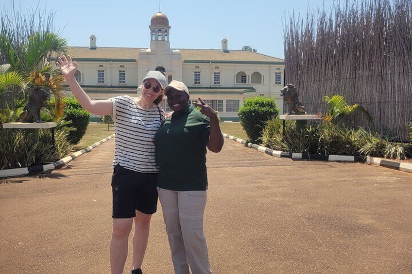 Two people posing in front of a building with a fountain and statues. 2