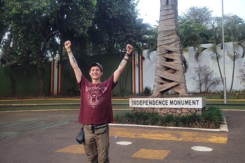 A person standing in front of the Independence Monument with arms raised. 3