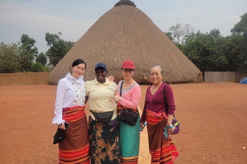 Four people standing in front of a thatched structure. 4