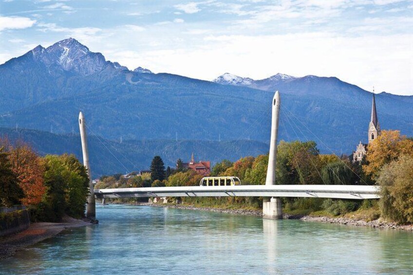 A bridge with a tram, a river, and mountains in the background. 3