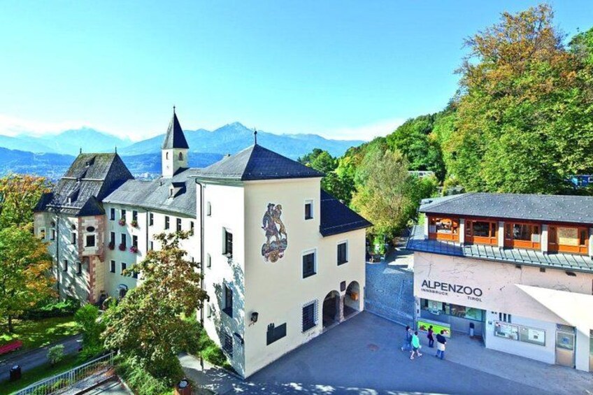 A town square with a building featuring a mural, a church, and a mountain backdrop. 5