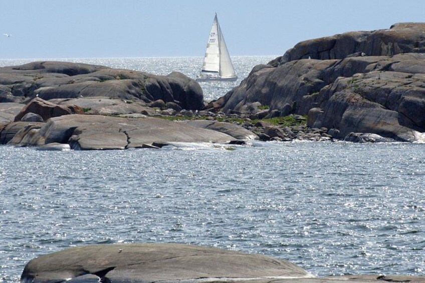 A sailboat navigating near rocky shores with clear water. 3