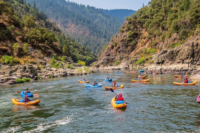 Un grupo de personas haciendo kayak en un río rodeado de colinas boscosas. 5