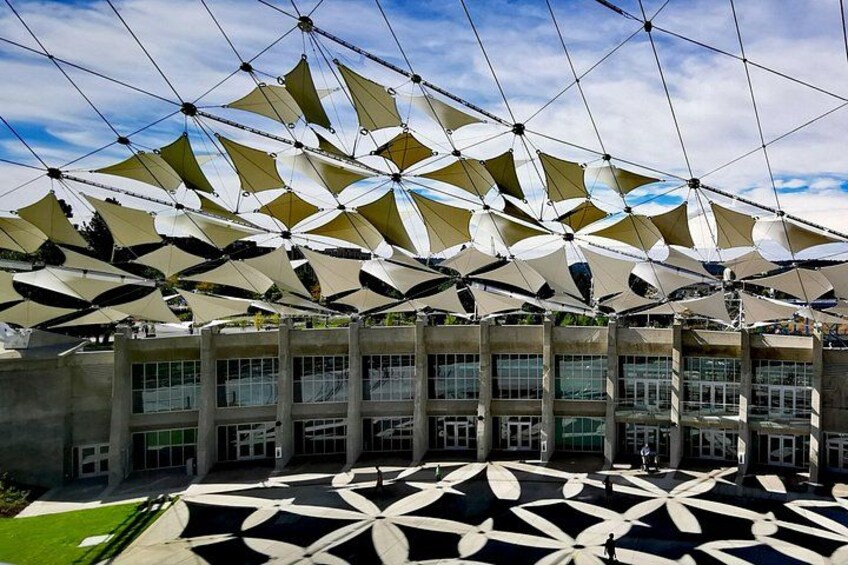 A modern building with a geometric patterned roof and a large open plaza. 3