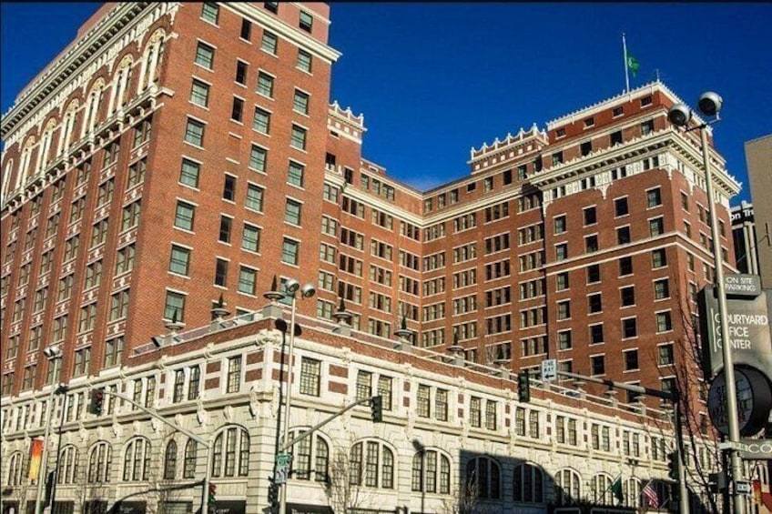 A large red brick building with multiple stories and a smaller white building in front. 2