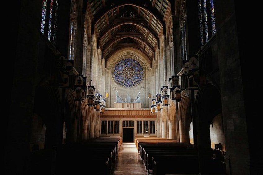 A cathedral interior with a large stained glass window, wooden pews, and arched ceilings. 4