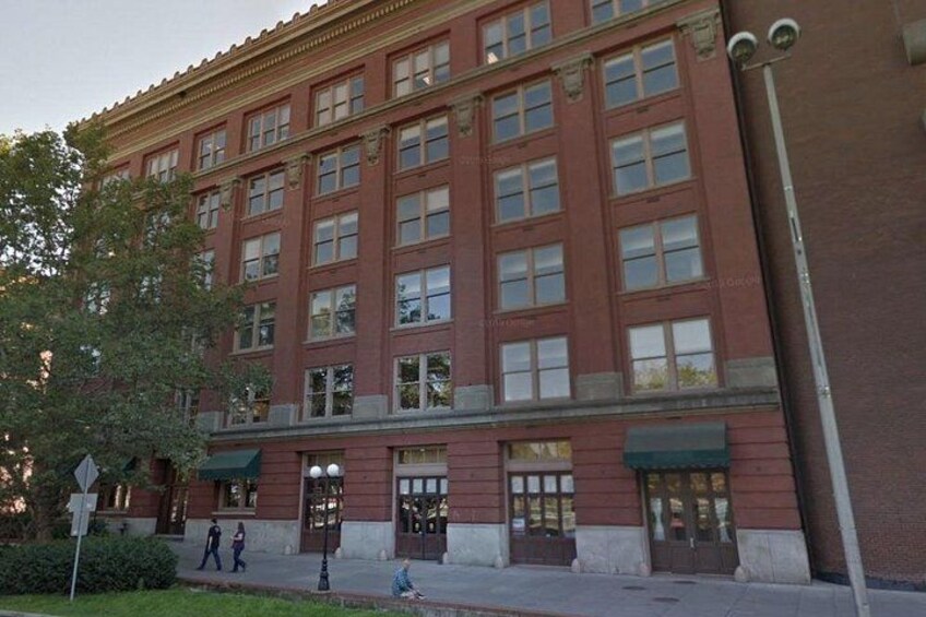 A red brick building with multiple windows and a green awning. 5