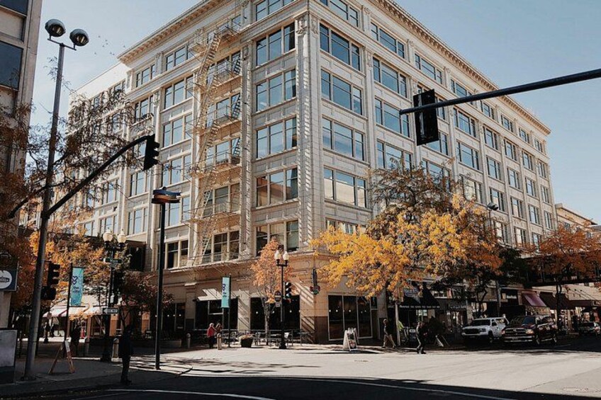 A multi-story building with a classic architectural style, a street intersection, and autumn-colored trees. 2