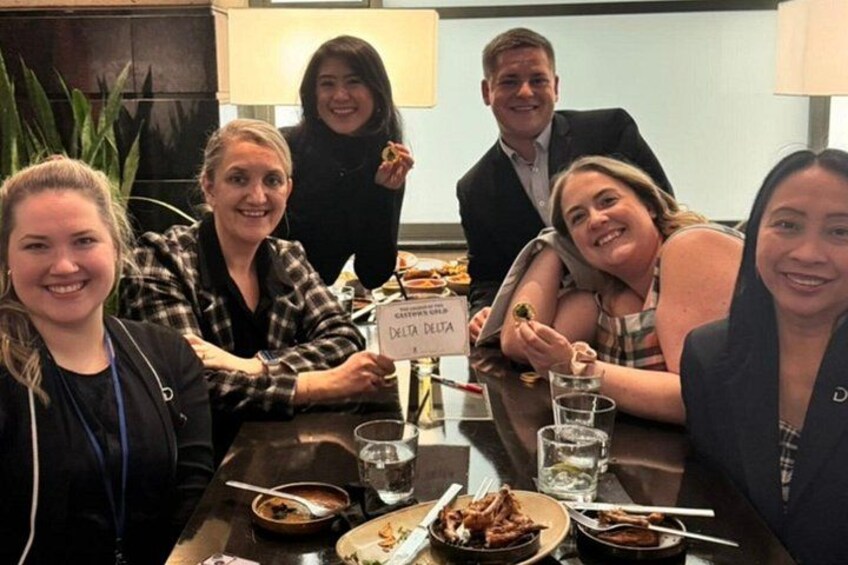 Un grupo de personas sentadas en una mesa con un letrero que dice 'DELTA'. 2