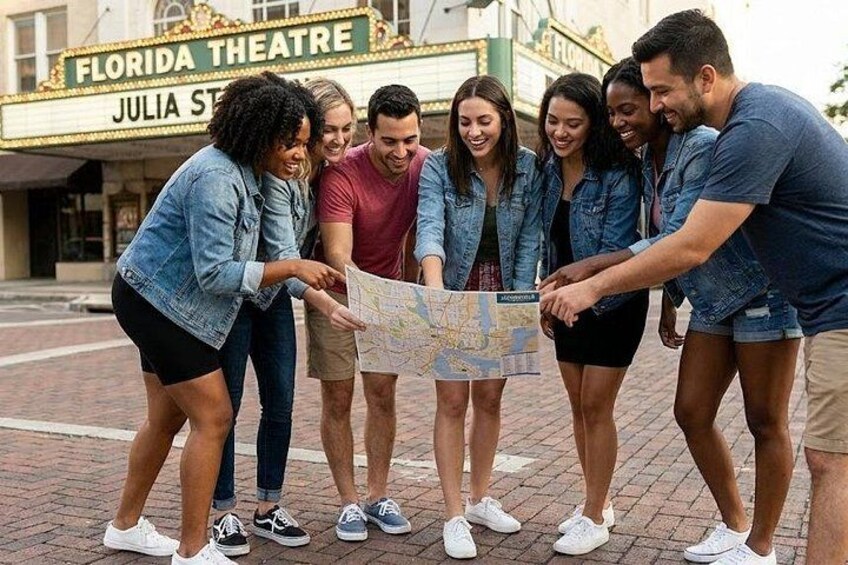 Un grupo de personas revisando un mapa frente a un teatro con un cartel que dice 'FLORIDA THEATRE JULIA ST'. 1