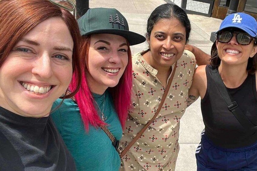 Four people standing close together outdoors. 3