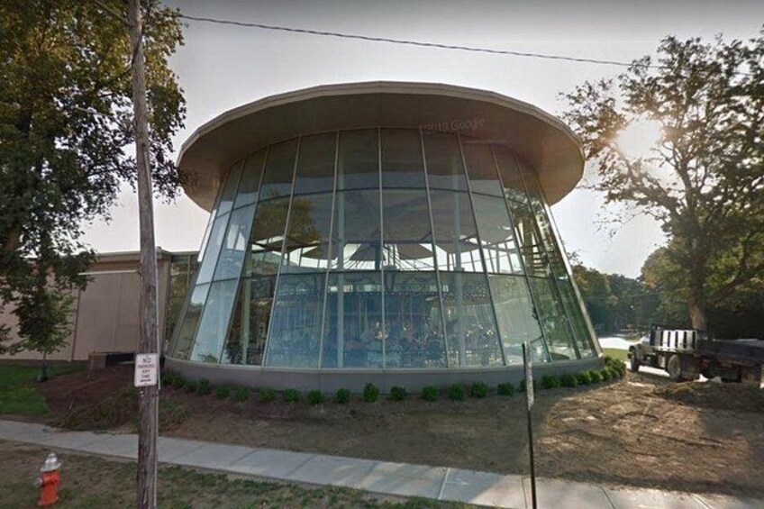 A modern building with a curved glass facade, surrounded by trees and a sidewalk. 4