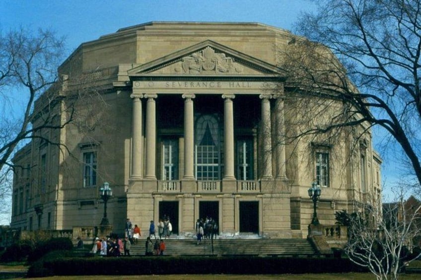 A large neoclassical building with a central entrance flanked by columns, a large arched window, and a sign reading 'SEVERANCE HALL'. 1