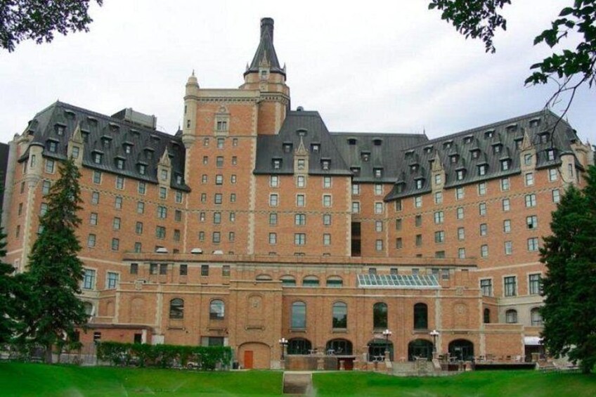 Un grand bâtiment historique doté d’une tour centrale, entouré d’une pelouse bien entretenue et d’arbres. 2