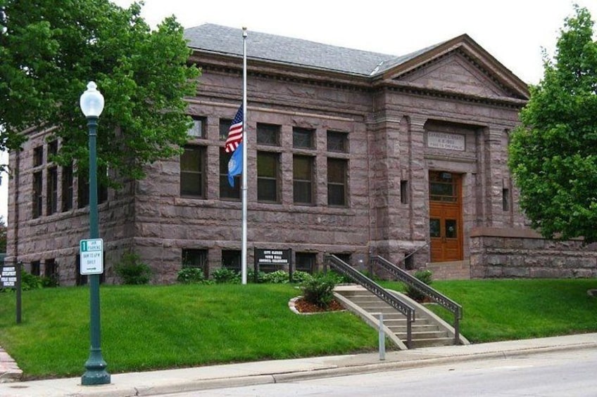 A stone building with a flagpole, a flag, and a staircase leading to the entrance. 5