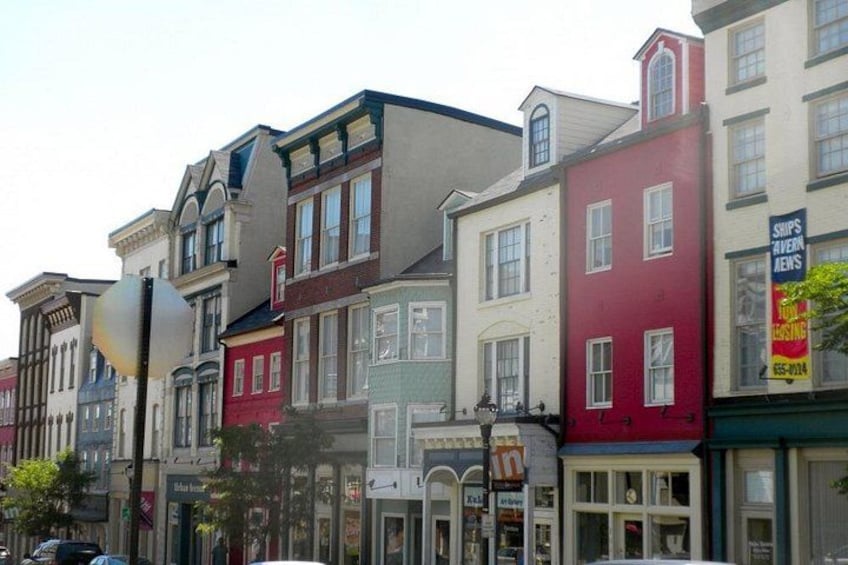Una hilera de edificios coloridos con escaparates, incluyendo un edificio rojo con un letrero de tienda. 2