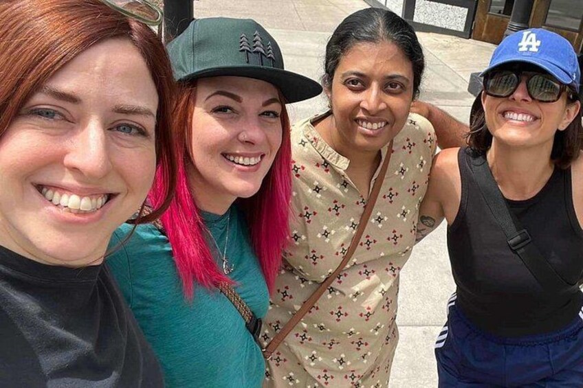 Four people standing outdoors, wearing casual clothing and hats. 2